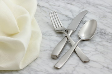 silverware and hemstitch napkin on antique carrara marble