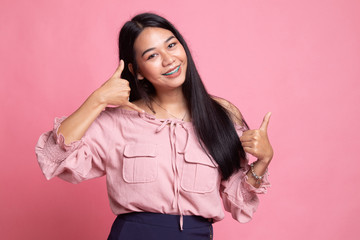Young Asian woman thumbs up show with phone gesture.