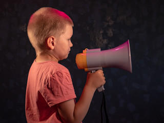 Child screaming into loudspeaker..Kid shouting through megaphone. Communication concept. Black background as copy space for your text