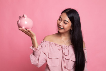 Young Asian woman with a pig coin bank.