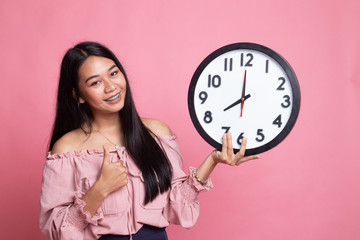 Young Asian woman thumbs up with a clock.