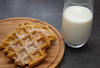 carrot waffles with powdered sugar on a wooden board with a glass of milk. Perfect healthy breakfast.