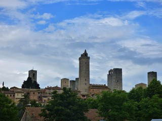 Fototapeta na wymiar Skyline View of the Towers of San Gimignano with a blue sky and white cloud background