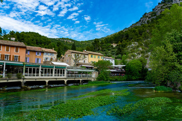 Fototapeta na wymiar South of France, view on small Provencal town of poet Petrarch Fontaine-de-vaucluse with emerald green waters of Sorgue river