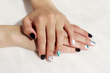 hands of a young girl with green, black and white manicure, with stickers.