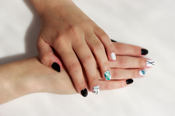 Obraz na płótnie Canvas hands of a young girl with green, black and white manicure, with stickers.