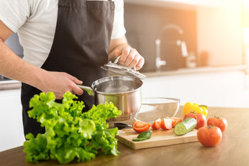 Obraz na płótnie Canvas Young trendy man cooking healthy food in the morning