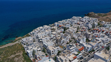 Aerial drone photo of iconic new settlement of Grotta perched on the hill and emerald clear rocky sea below, Naxos island, Cyclades, Greece