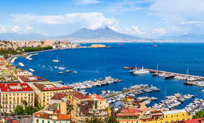 Naples city and port with Mount Vesuvius on the horizon seen from the hills of Posilipo. Seaside landscape of the city harbor and golf on the Tyrrhenian Sea