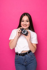 Fototapeta premium Young pretty asian tourist woman with camera standin isolated on pink background