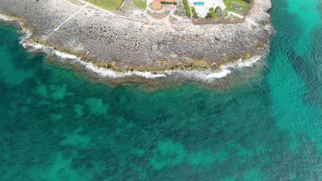 Aerial tilt up shot revealing the beautiful rocky coastline and sea in Monopoli, Southern Italy, with houses along the beach