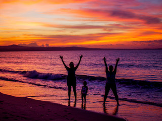 Silhouette of two women on the beach with a child