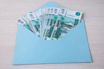 On the table a blue envelope with a Russian banknotes in denominations of one thousand rubles