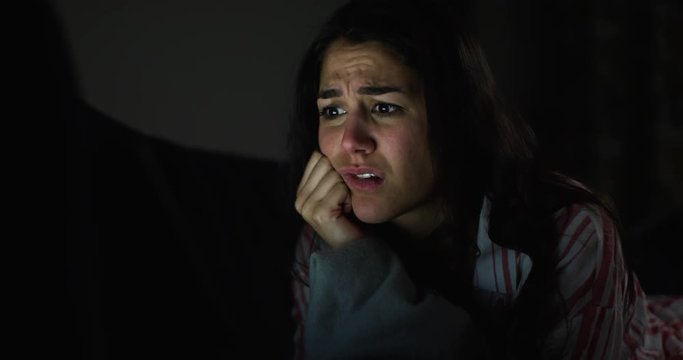 4K Close up with girl's reactions while watching scary movie alone in the dark. Slow motion.