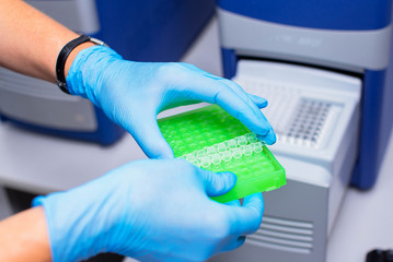 Dna test in the lab. the technician inserts the test tubes into the dna analyzer. Gloved hands close up