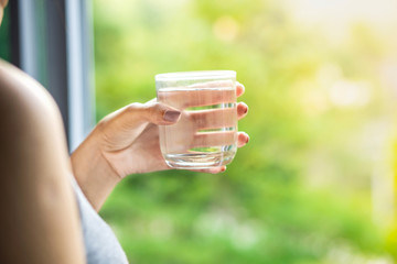 Asian woman hand holding glass of fresh and clean water drinking in the morning with nature background 