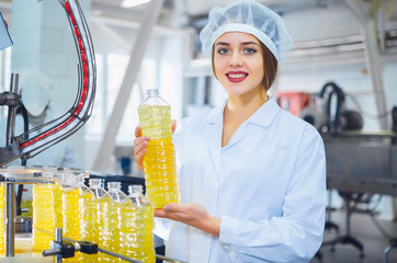 Young beautiful girl in white overalls at the plant for the production of sunflower and olive oil....