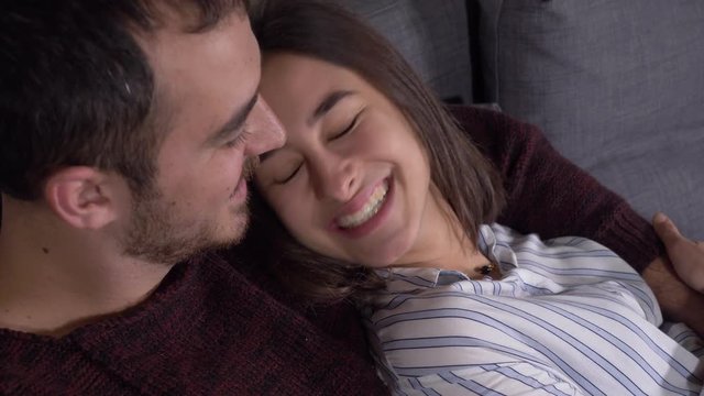 Intimacy, Love, complicity.Tenders young lovers cuddling,smiling on couch