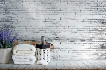 Mockup folded towel with soap and houseplant on wooden table with old brick wall.