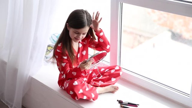 little girl playing with her hair and looking at a mirrow