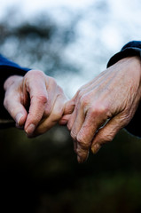 Old couple holding hands closely, close up