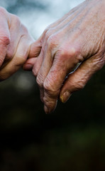 Fototapeta premium Old couple holding hands closely, close up