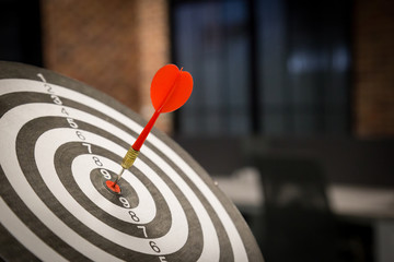 Red dart arrow hitting in the target center of dartboard on bullseye with sun light vintage style,...