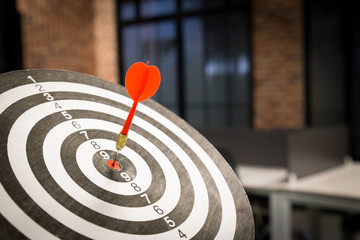 Red dart arrow hitting in the target center of dartboard on bullseye with sun light vintage style,...