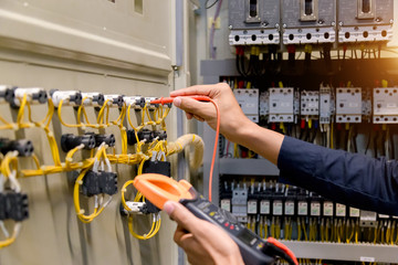 Electrician engineer work  tester measuring  voltage and current of power electric line in electical cabinet control.