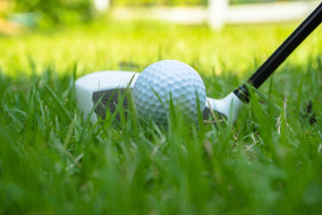 Golf ball and golf club in beautiful golf course at Thailand. Collection of golf equipment resting on green grass with green background