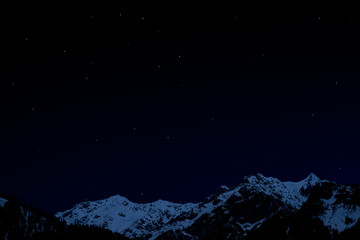 Obraz premium mountain ridge covered with snow-capped peaks winter night with stars and milky way galaxy