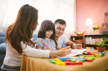 Portrait of happy family daughter girl is learning drawing book together with parent