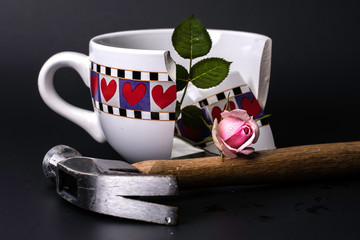 Broken Heart Cup with got shattered with hammer and pink rose on Black Background