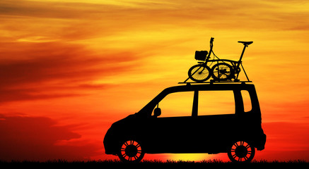 Fototapeta na wymiar Silhouette of bicycle on the roof of car on sunset