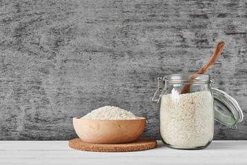 Rice grains in wooden bowl and glass jar