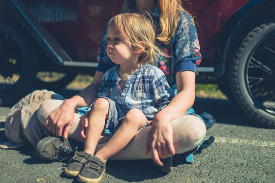 Mother and toddler relaxing by vintage car