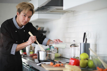 Asian cook in the kitchen prepares food in a cook suit
