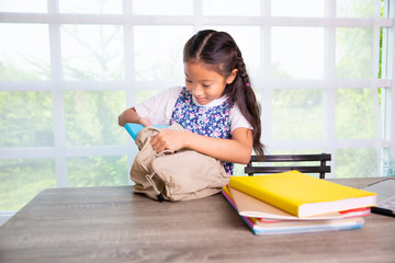 Primary school girl packing books to the bags