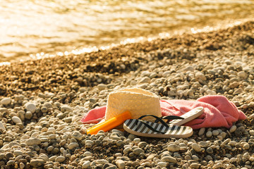 Sun hat and flip flops on stone beach