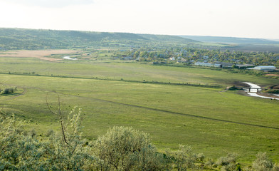 rural village in the green valley with river and high voltage electric poles across the valley