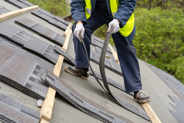 Workman install tile on roof of new house under construction