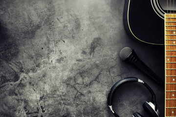 Guitar and accessories on a stone background. Desk musician, headphones, microphone.