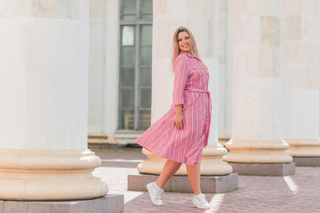 Young stylish woman walking on the city street at summer. Casual fashion, linen dress look. Plus...