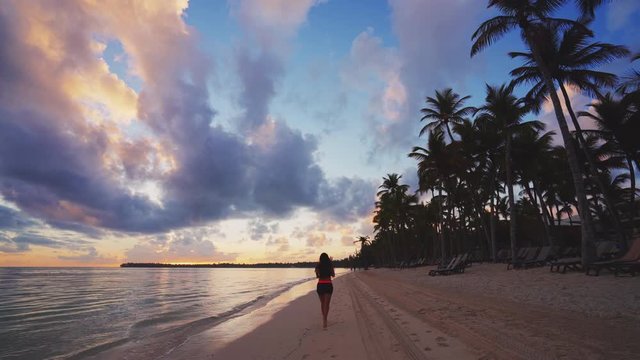 Girl running on tropical beach early in the morning. Sunrise over caribbean island Dominican Republic
