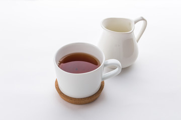 A cup of black tea with and milk jug isolated on white background