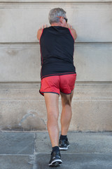 Fototapeta na wymiar Elderly Man Warming-up and Stretching before a Marathon in the City