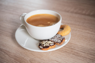 Espresso coffee in modern white cup decorated with cookies on wooden table