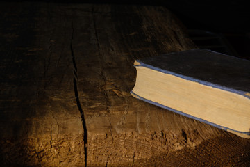 Old book lies on a dark board. Dark still life. Concept - interest in history