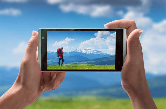 Girl backpacker in a mountains on a smartphone