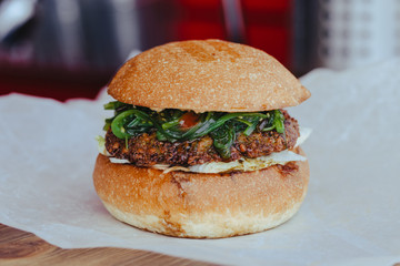Delicious fresh homemade vegetarian cheese burger with chuka salad, cheese, tomatoes, lettuce and onion rings in kraft paper.
